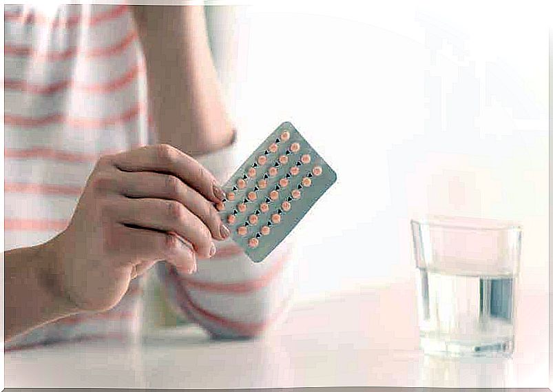 A woman holding a packet of birth control pills