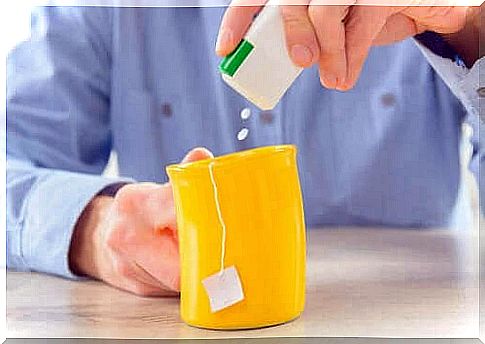 Man pours sweetener into a cup of tea