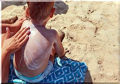 Boy gets smeared sunscreen on his back as part of caring for children's skin in the summer